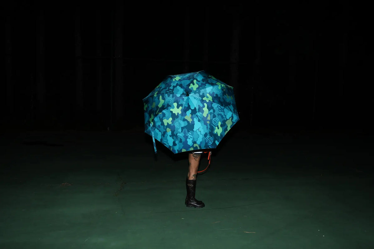 Person standing under a camo-print umbrella at night